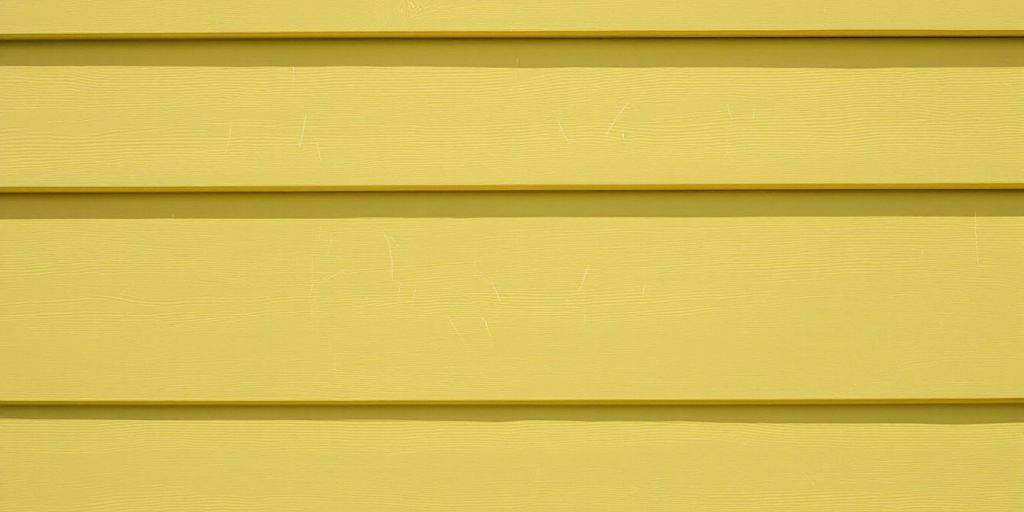 Close-up of scratched vinyl siding on a house.