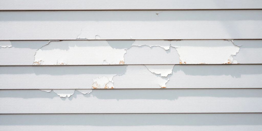 House exterior with peeling paint on vinyl siding.