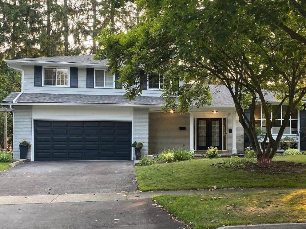 clean and crisp looking house with white painted siding, brick, trim, and accent colour painted dark blue on doors and shutters.
